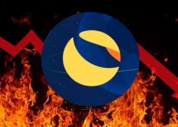 Logo del cripto LUNA sobre fuego y una flecha roja fracturada descendiente detrás