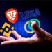 Una mano masculina abierta y los logos de VISA, Binance y Brave encima