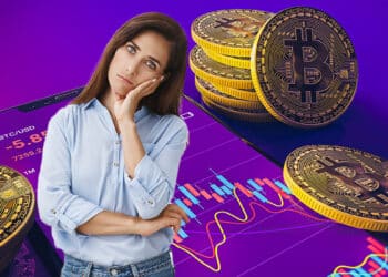 mujer con gesto de duda en frente de moneda de bitcoin con gráfico de precio en pantalla de teléfono