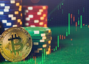 Moneda dorada de bitcoin sobre una mesa de poker con fichas de casino.