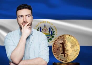 Hombre pensativo junto a un bitcoin y la bandera de El Salvador.