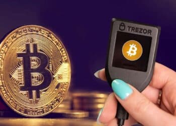 Trezor junto a monedas de Bitcoin.