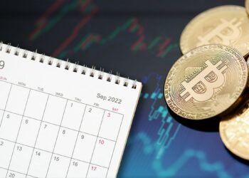 monedas de bitcoin junto a calendario de semptiembre con gráficos de precio en el fondo