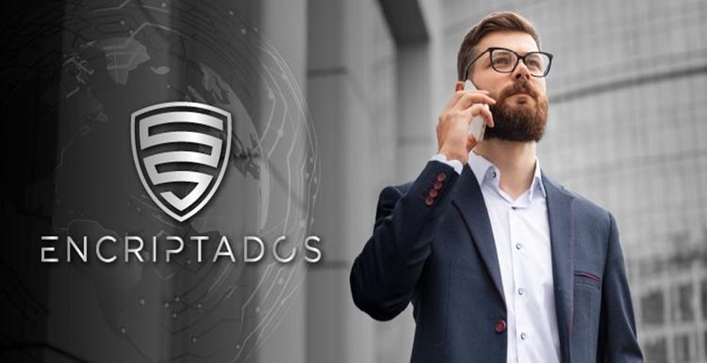 Hombre de negocios hablando por un teléfono celular junto al logo de la empresa Emcriptados.io