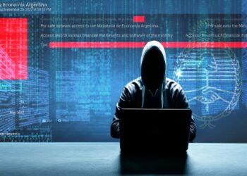 hacker en computadora con página del ministerio de Economía dde Argentina y código en el fondo