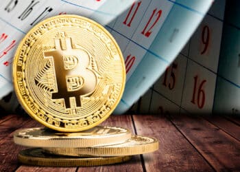 moneda de bitcoin sobre mesa con calendario pasando hojas en el fondo