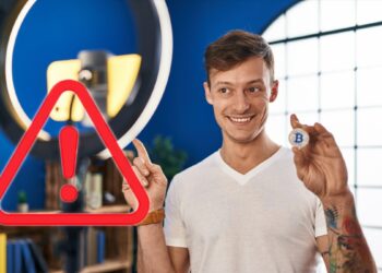 signo de advertencia en frente de influencer sosteniendo moneda de bitcoin