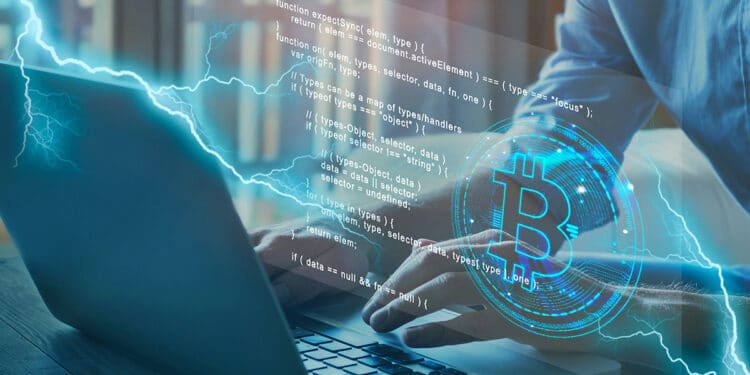 persona tecleando en computadora con logo de bitcoin y código proyectando desde la pantalla