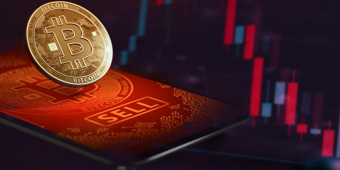 moneda de bitcoin sobre pantalla de teléfono con gráfico bajista en el fondo