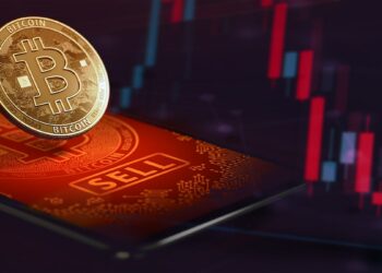 moneda de bitcoin sobre pantalla de teléfono con gráfico bajista en el fondo