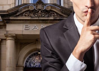Banquero guardando un secreto sobre bitcoin junto a banco.