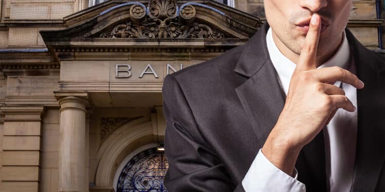 Banquero guardando un secreto sobre bitcoin junto a banco.