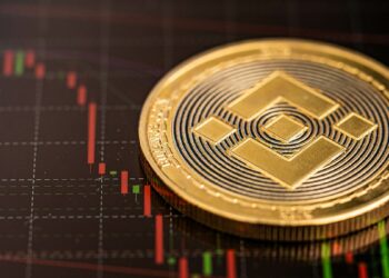 moneda de Binance sobre superficie con gráfico de precio descendiendo