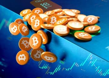 monedas de bitcoin cayendo del borde de una mesa con gráficos de exchange