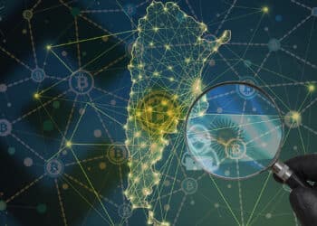 Mano sostiene lupa con bandera de Argentina sobre mapa de Argentina con red de bitcoin y logo de binance