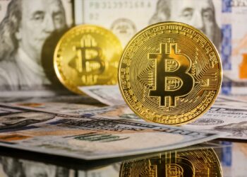 moneda de bitcoin sobre billetes de dólares