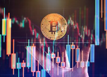 moneda de bitcoin sobre plataforma sostenida por mano con gráficos de precio en el fondo