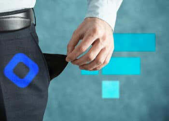 Persona con bolsillos vacíos y logo de BLockfi en pantalón y logo de FTX al fondo