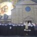 monjas y sacerdote en frente de iglesia con moneda de bitcoin brillando en el fondo