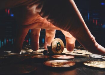mano agarrando bitcoin con gráfico de precio en el fondo