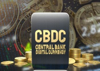 tablet rodeada de CBDC y monedas de bitcoin partidas en el fondo