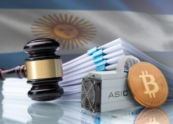 miniatura de moneda de bitcoin apoyada en minero asic junto a martillo de juez con documentos y bandera de argentina en el fondo