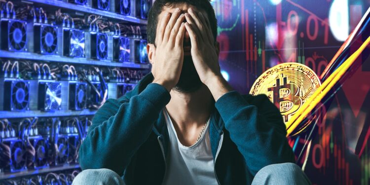 hombre preocupado cubriendo su cara con las manos con mineros asic de granja junto a moneda de bitcoin entre cables con gráfico bajista de precio en el fondo