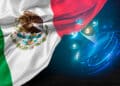 Una bandera de México con un globo terráqueo de fondo en el que se visualiza el logo de bitcoin.