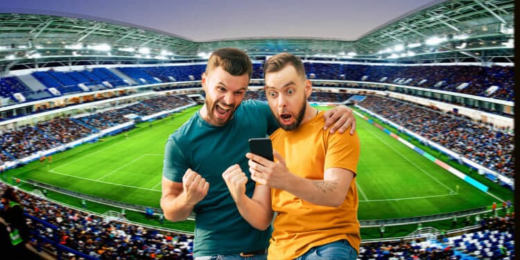 hombres celebrando con telefono en mano en estadio de futbol