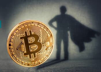 moneda de bitcoin proyectando sobre ade superheroe con logos de FTX en el fondo