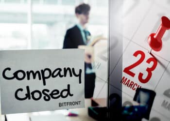 letrero de compañía cerrada con logo de Bitfront pegado en ventana de oficina con persona recogiendo pertenencias con fecha marcada en calendario de marzo superpuesta