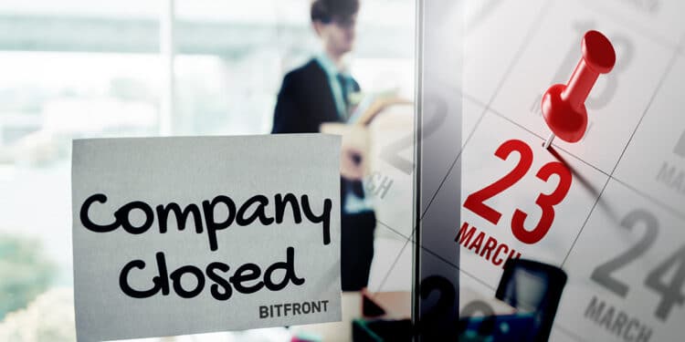 letrero de compañía cerrada con logo de Bitfront pegado en ventana de oficina con persona recogiendo pertenencias con fecha marcada en calendario de marzo superpuesta