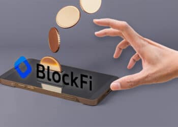 mano alcanzando telefono con logo de blockfi y criptomonedas