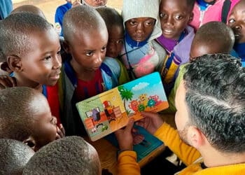 niños alrededor de mastro leyendo libro infantil