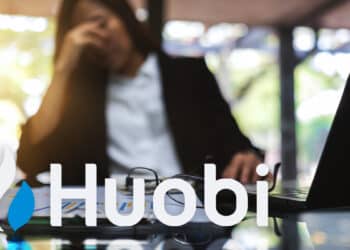 Logo de Huobi sobre escritorio con mujer empresaria con gesto de preocupación en el fondo