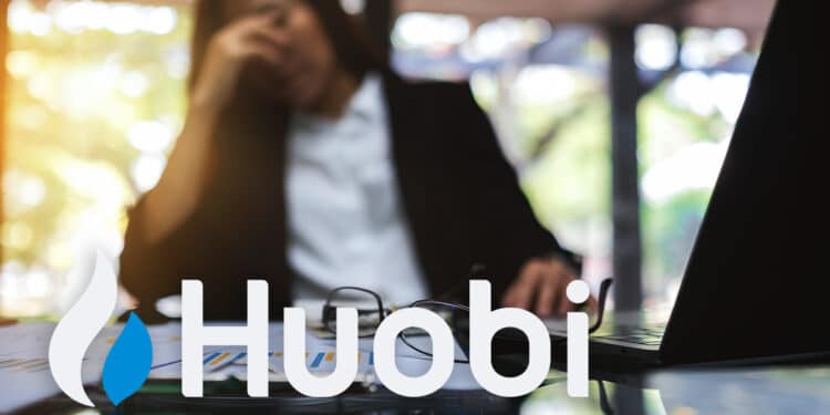 Logo de Huobi sobre escritorio con mujer empresaria con gesto de preocupación en el fondo