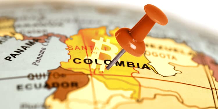 alfiler clavado en mapa mundi sobre ubiación de Colombia con logo de Bitcoin