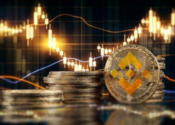 monedas apiladas del token BNB, de Binance, con gráfico de precio en el fondo