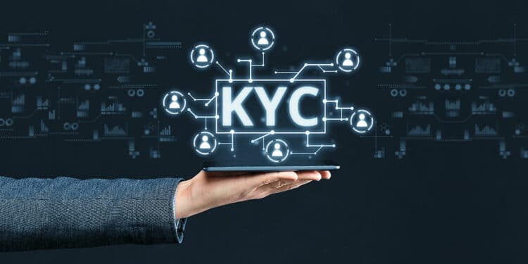 Mano de persona sosteniendo teléfono con gráficos y siglas KYC