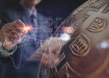 Analista revisa gráfico de precio junto a moneda de bitcoin