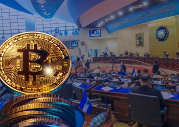 moneda de bitcoin sobre monedas apiladas con imagen de la asamblea legislatica de El salvador en el fondo