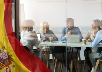 personas reunidas en oficina con bandera de España superpuesta