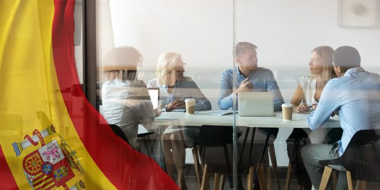 personas reunidas en oficina con bandera de España superpuesta