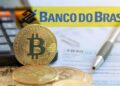 monedas de bitcoin apoyada en calculadora junto a documentos de impuestos con marcador del Banco do Brasil