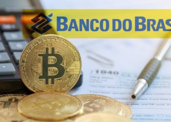 monedas de bitcoin apoyada en calculadora junto a documentos de impuestos con marcador del Banco do Brasil