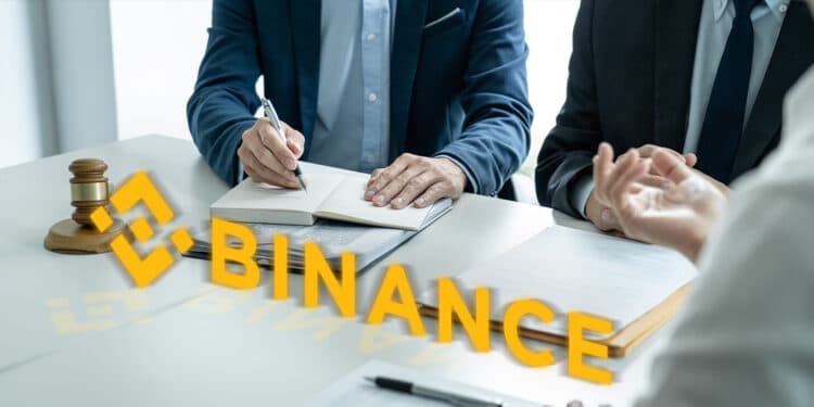 Logo de Binance en mesa con personas, documentos y maso de juez llegando a un acuerdo