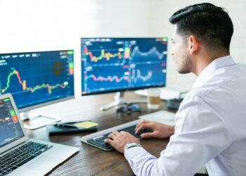 trader observando gráficos de mercado en pantallas de computadora con logo de Bianance