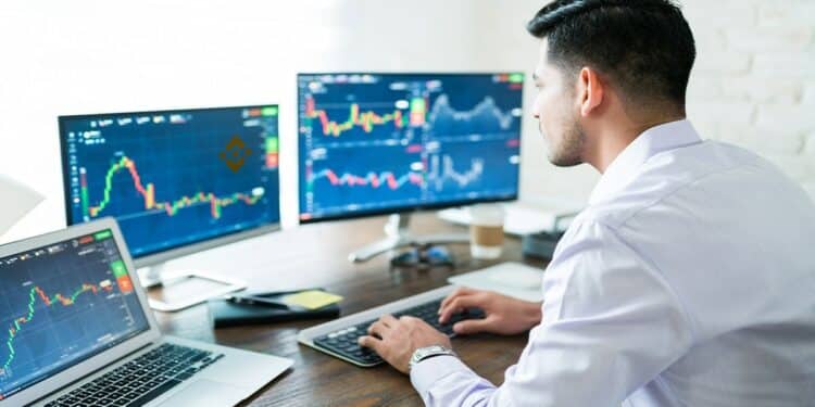 trader observando gráficos de mercado en pantallas de computadora con logo de Bianance