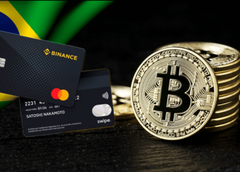 Tarjetas de binance y mastercard junto a bitcoin y bandera de Brasil.