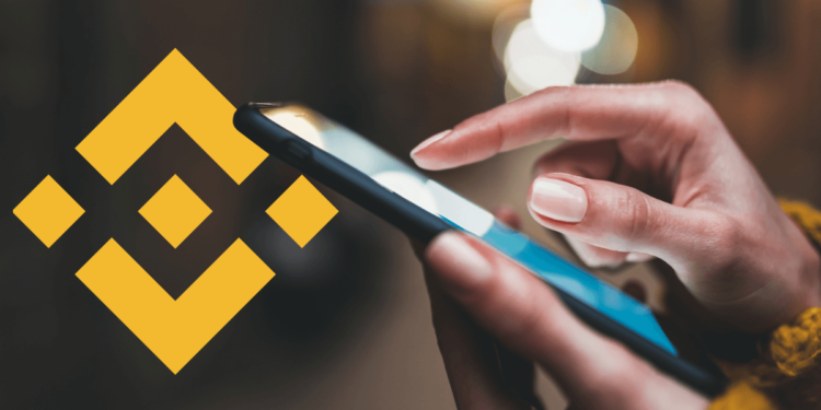 persona usando teléfono móvil con logo de Binance en el fondo
